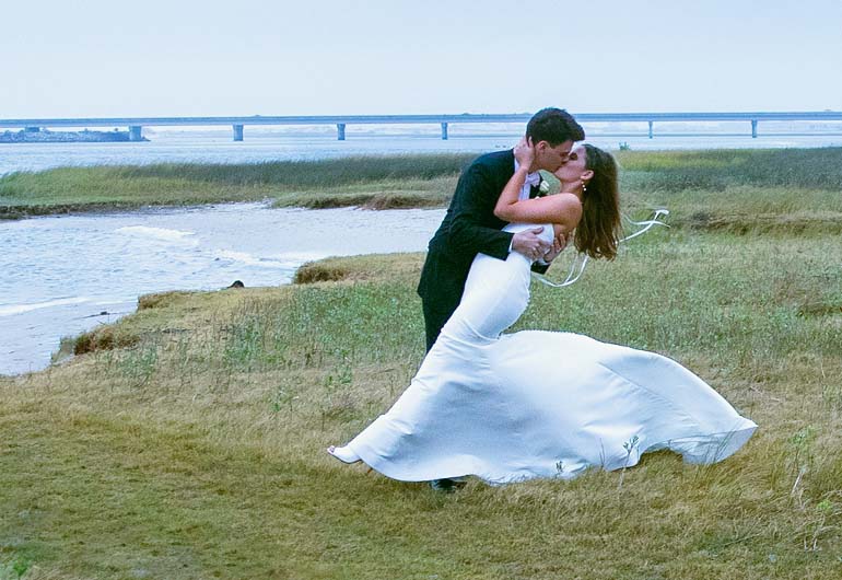 groom dipping bride by a lake kissing